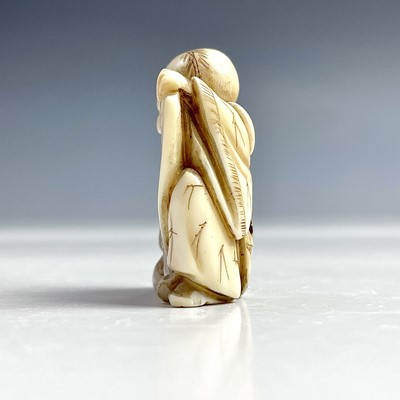 Lot 547 - A Japanese netsuke of a seated man holding a...