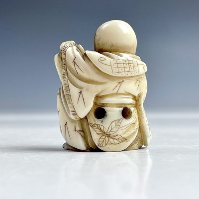 Lot 547 - A Japanese netsuke of a seated man holding a...