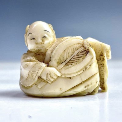 Lot 548 - A Japanese ivory netsuke of a boy holding a...