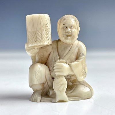 Lot 551 - A Japanese ivory netsuke of a seated figure...