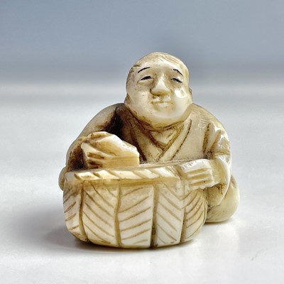 Lot 555 - A Japanese ivory netsuke of a seated figure...