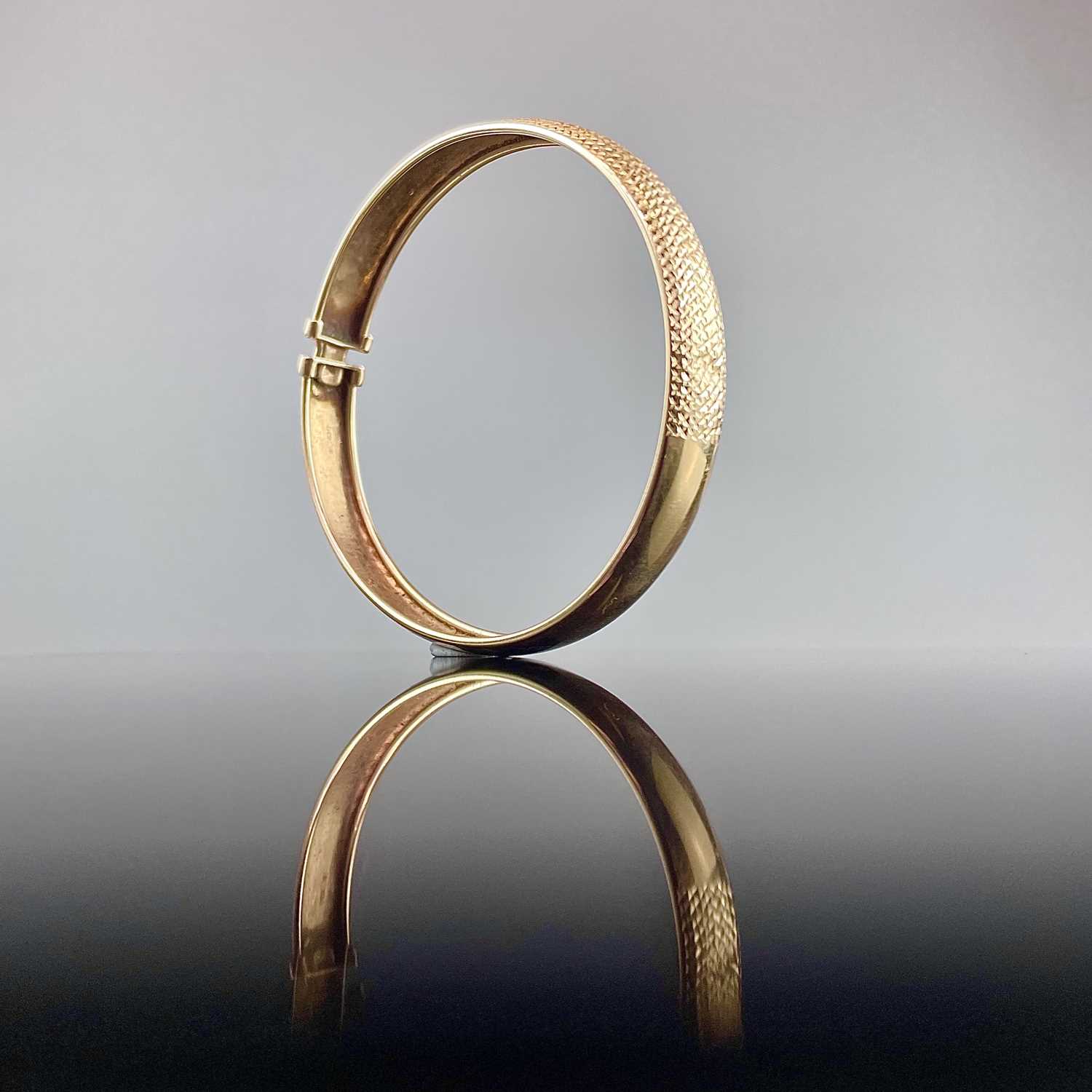 Lot 553 - A 9ct gold bangle with textured front,