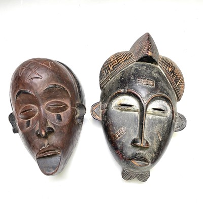 Lot 178 - An African carved wood mask together with...