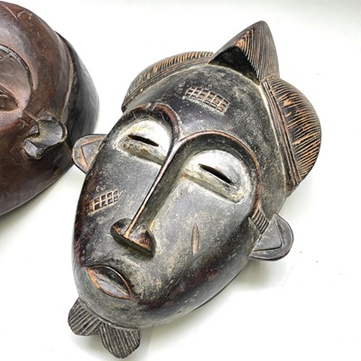 Lot 178 - An African carved wood mask together with...