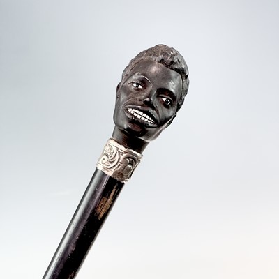 Lot 89 - An ebonised walking stick with a carved top in...