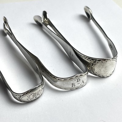 Lot 134 - Three Georgian silver bright cut sugar nips,...