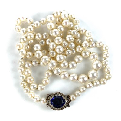 Lot 137 - A graduated pearl necklace with 9ct clasp set with an oval synthetic blue sapphire.