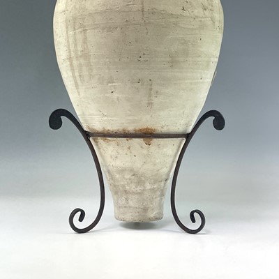 Lot 210 - A terracotta twin handled storage jar on a...