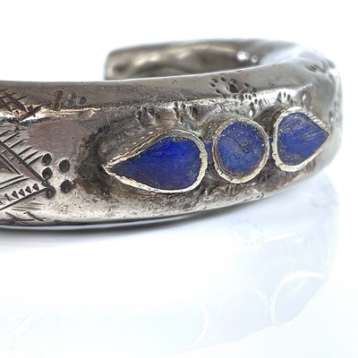 Lot 274 - A tribal white metal lapis lazuli set bangle.