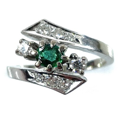 Lot 148 - A 14ct white gold diamond and emerald crossover nine stone ring.
