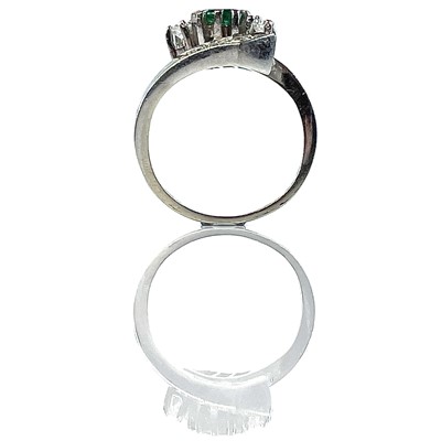 Lot 148 - A 14ct white gold diamond and emerald crossover nine stone ring.