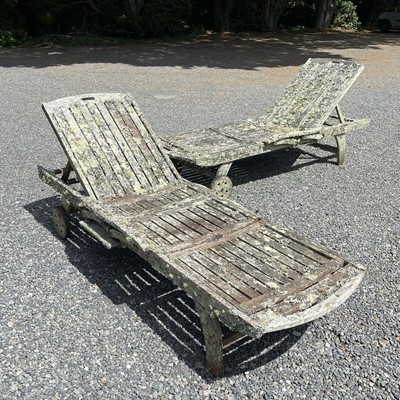 Lot 602 - A pair of teak sunloungers with adjustable backs.