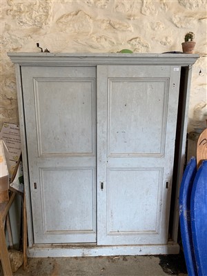 Lot 409 - A painted pine cupboard with sliding doors.