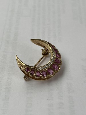 Lot 7 - A modern 9ct gold diamond and ruby crescent brooch