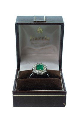 Lot 143 - An 18ct white gold emerald and diamond cluster ring.