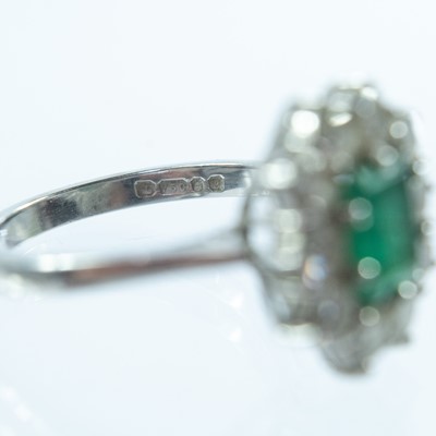 Lot 143 - An 18ct white gold emerald and diamond cluster ring.