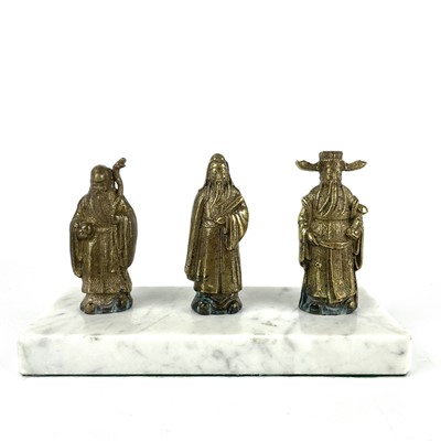 Lot 418 - Three Chinese bronze figures of Immortals on a white marble base, early-mid 20th century.