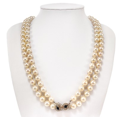 Lot 338 - A Swedish cultured pearl necklace with double 18ct white gold diamond and sapphire cluster clasps.