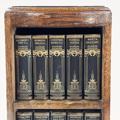 Lot 1877 - The works of Charles Dickens contained in a small oak bookcase.