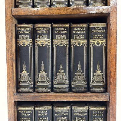 Lot 1877 - The works of Charles Dickens contained in a small oak bookcase.