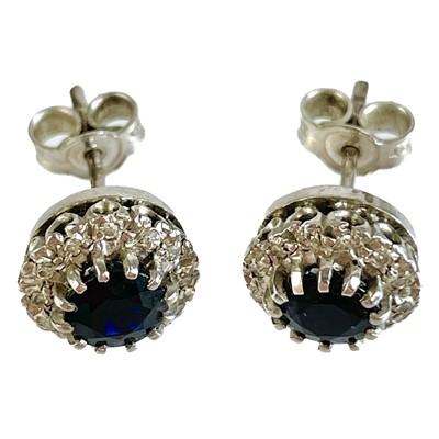 Lot 107 - A pair of 9ct white gold diamond and sapphire cluster stud earrings.