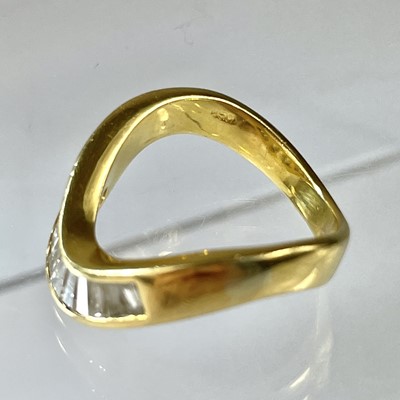 Lot 21 - A high purity gold diamond set eleven stone wishbone ring.