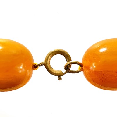 Lot 431 - An egg yoke butterscotch amber bakelite oval bead necklace.