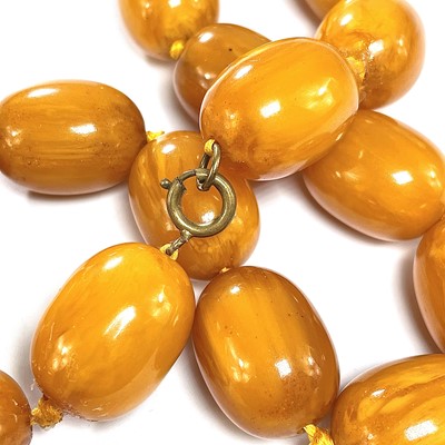 Lot 431 - An egg yoke butterscotch amber bakelite oval bead necklace.