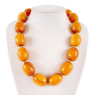 Lot 431 - An egg yoke butterscotch amber bakelite oval bead necklace.