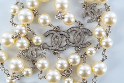 Lot 559 - A Chanel white metal cultured pearl and white gem set CC long necklace.
