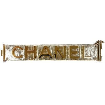 Lot 560 - A Chanel light gold tone and gold calfskin leather logo bracelet.