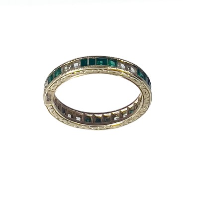 Lot 48 - A 9ct gold white and green stone set full eternity ring.