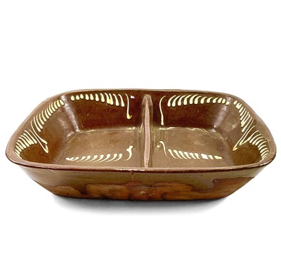 Lot 104 - A slipware two division earthenware pie dish.