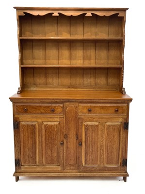 Lot 1829 - An Arts and Crafts light oak dresser in two parts.