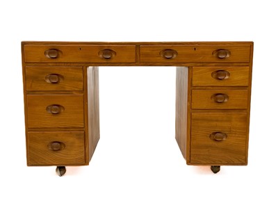 Lot 1856 - An Ercol Windsor light elm kneehole desk.