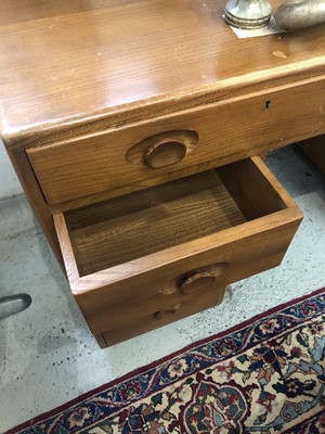 Lot 1856 - An Ercol Windsor light elm kneehole desk.