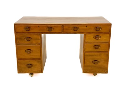 Lot 1856 - An Ercol Windsor light elm kneehole desk.