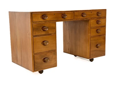 Lot 1856 - An Ercol Windsor light elm kneehole desk.