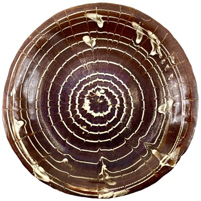 Lot 225 - A 19th century circular slipware dish with spiral comb decoration.