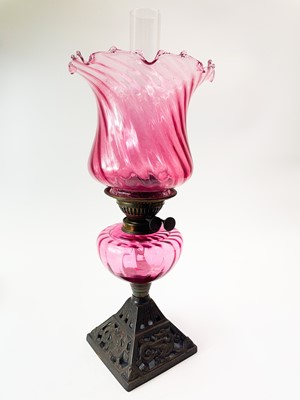 Lot 203 - A Victorian cast iron and cranberry glass oil lamp.