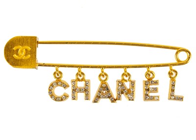 Lot 354 - A Chanel gold tone pin brooch with crystal set charm logo.