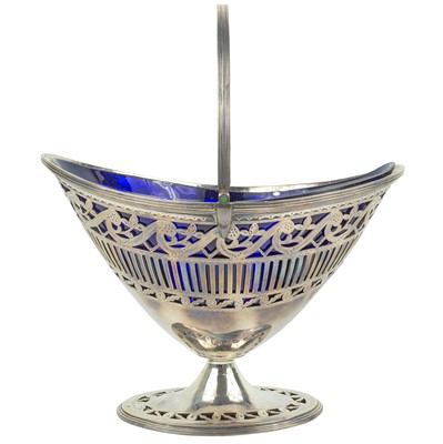 Lot 31 - A George III Irish silver pedestal swing-handled sugar basket with a blue glass insert.