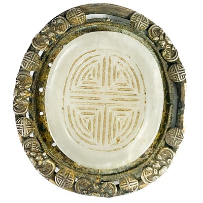 Lot 468 - A Chinese carved white and silver mounted oval brooch.