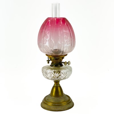 Lot 180 - A Victorian brass oil lamp with glass oil reservoir cranberry shade