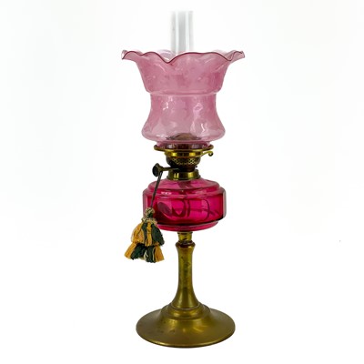 Lot 181 - A Victorian brass oil lamp with cranberry glass reservoir and cranberry shade.