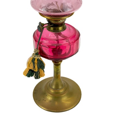 Lot 181 - A Victorian brass oil lamp with cranberry glass reservoir and cranberry shade.