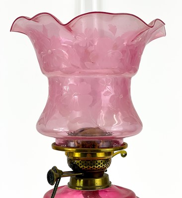 Lot 181 - A Victorian brass oil lamp with cranberry glass reservoir and cranberry shade.