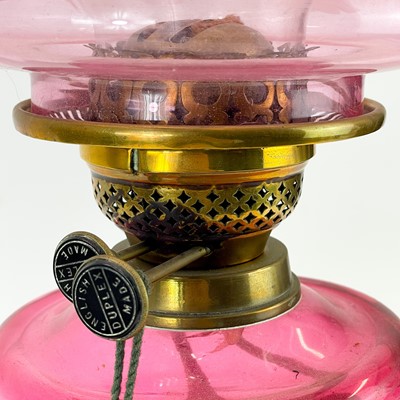 Lot 181 - A Victorian brass oil lamp with cranberry glass reservoir and cranberry shade.