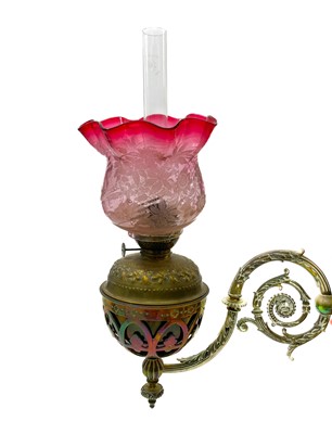 Lot 185 - A pair of Victorian wall bracket brass oil lamps with cranberry glass shades.